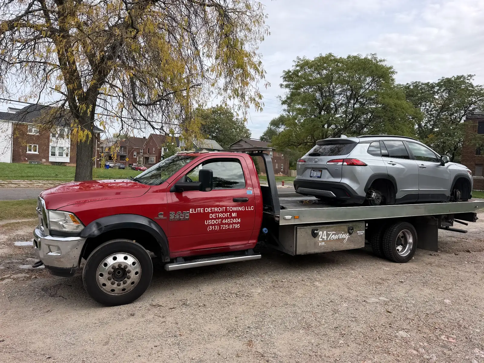 Elite Detroit Towing red Ram flatbed with company lettering carrying an SUV in Detroit
