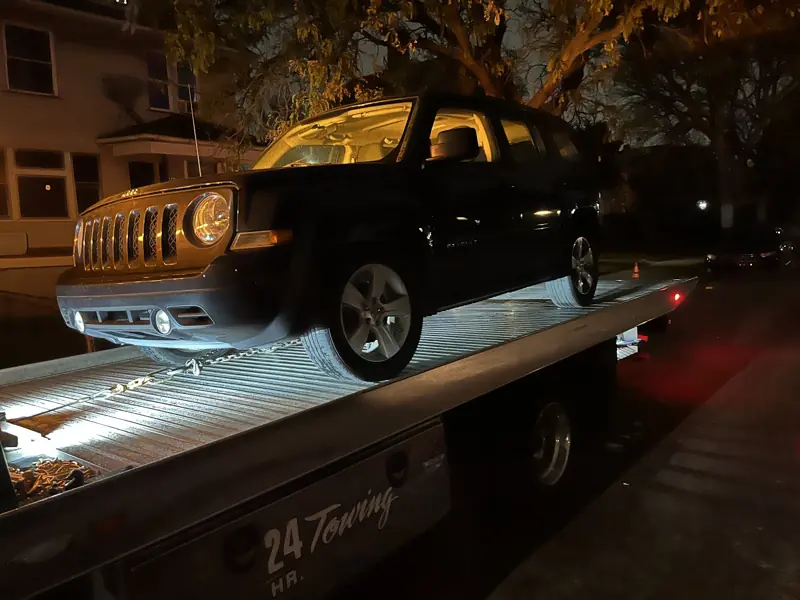 Jeep loaded on an Elite Detroit Towing flatbed at night
